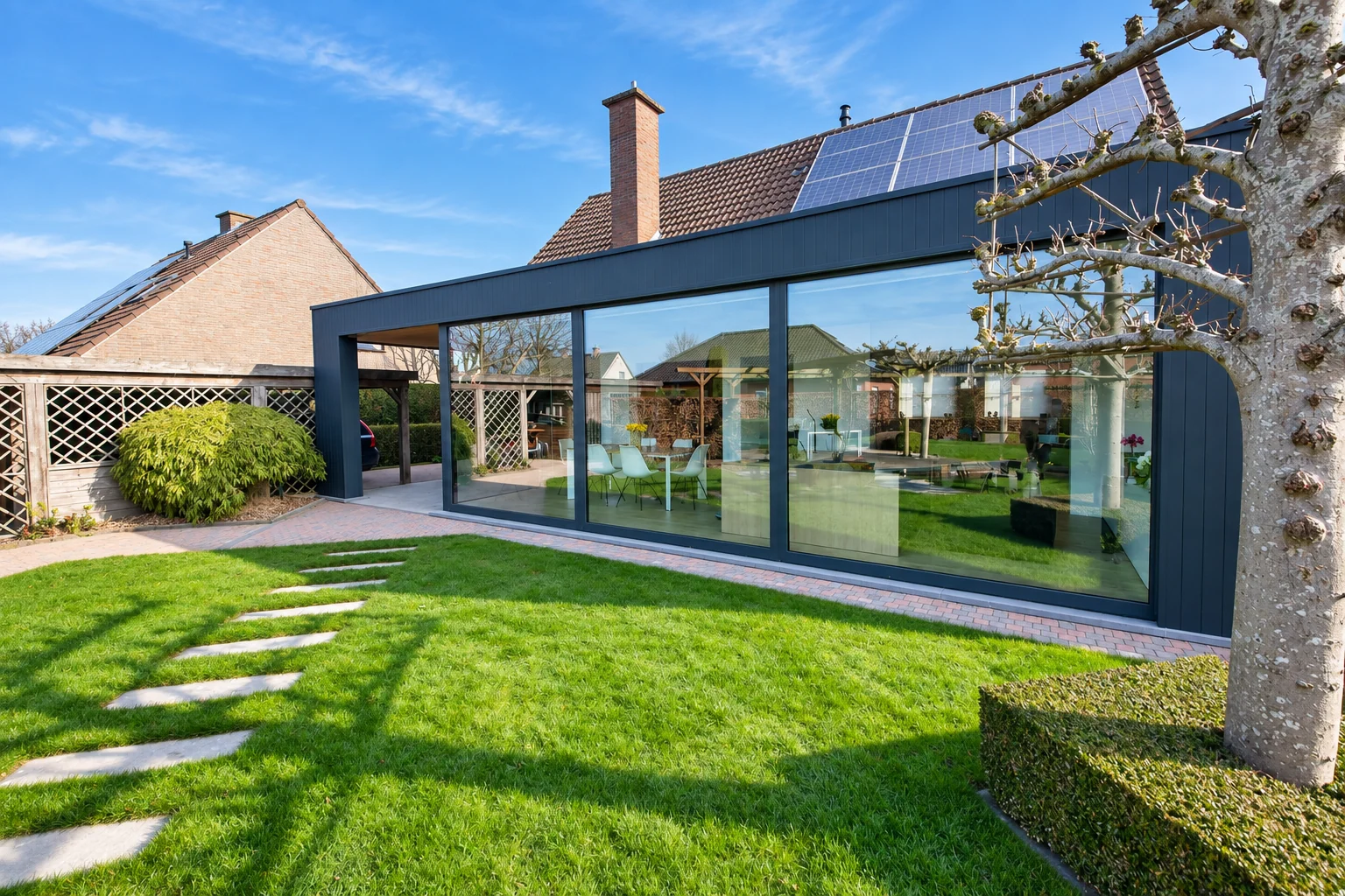 Moderne woonuitbreiding met grote glaspartijen en tuinzicht in West-Vlaanderen